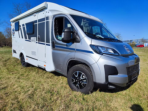 Wohnmobil Carado seitlich auf grüner Wiese.