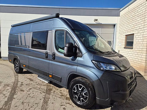 Moderne Fiat Ducato Camper mit schwarzen Felgen und Sonnenmarkise.